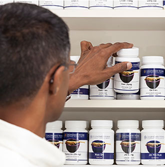 Dr. Natarajan grabbing Chinese herbs off a shelf