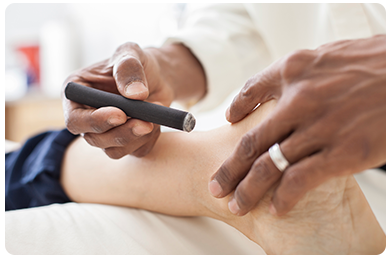 Dr. Natarajan using a Heating Pen for Moxa Burning on a clients ankle