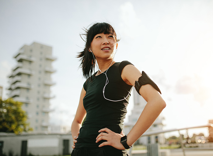 Young woman pausing on a run with headphones